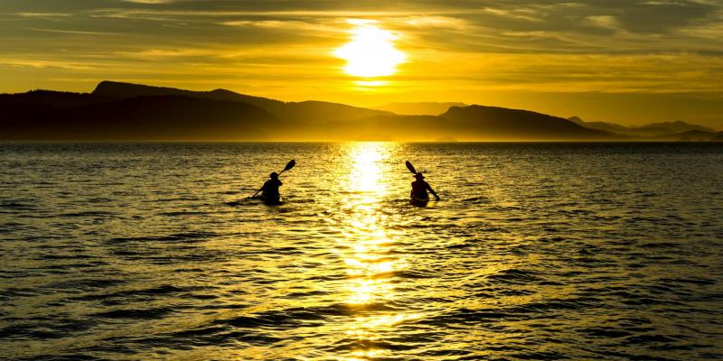 Kayaks paddling into the sunset, Southern Gulf Islands, British Columbia